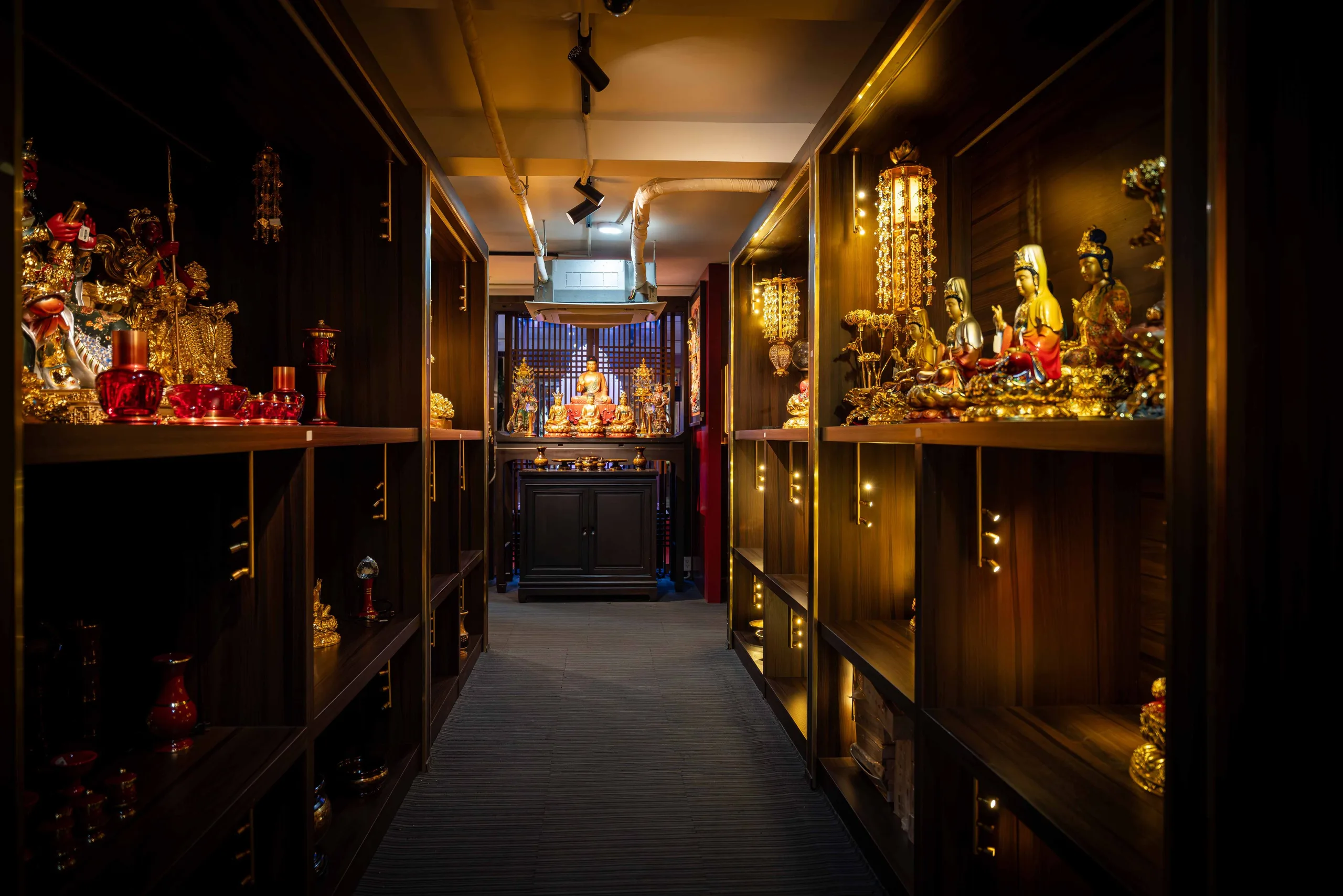 Lối đi giữa hai dãy kệ trưng bày tôn tượng và pháp khí trong showroom Diệu Tướng Am